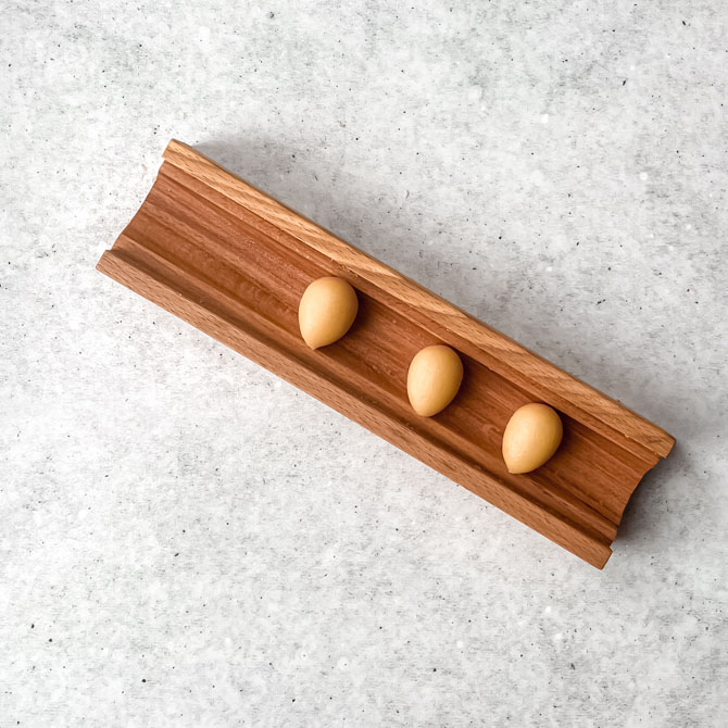 Hands shaping marzipan into small egg shapes