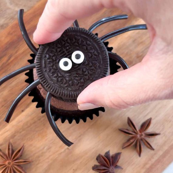 Adding candy legs and eyes to spider cupcakes