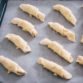 Unbaked almond crescent rolls on a baking sheet