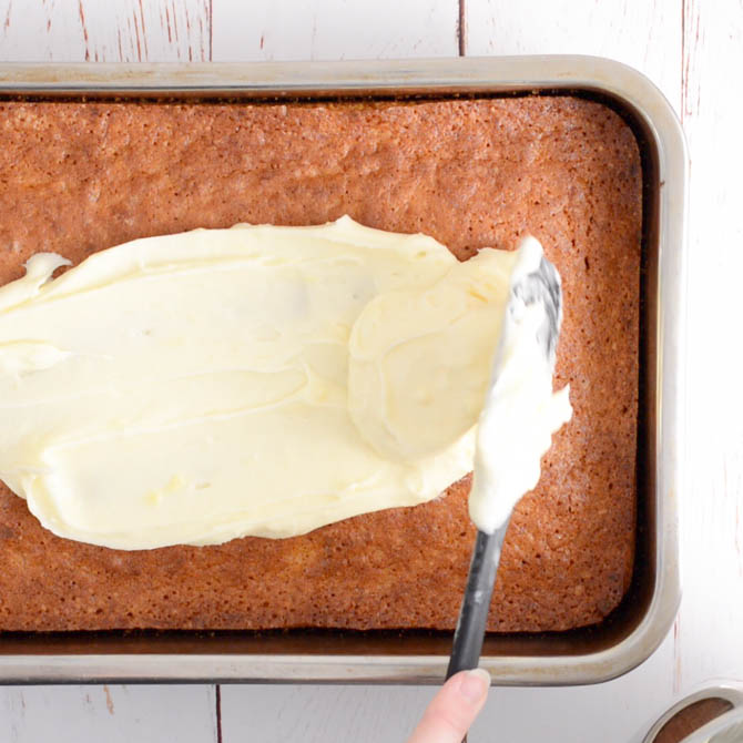 Cream cheese frosting spread over carrot cake