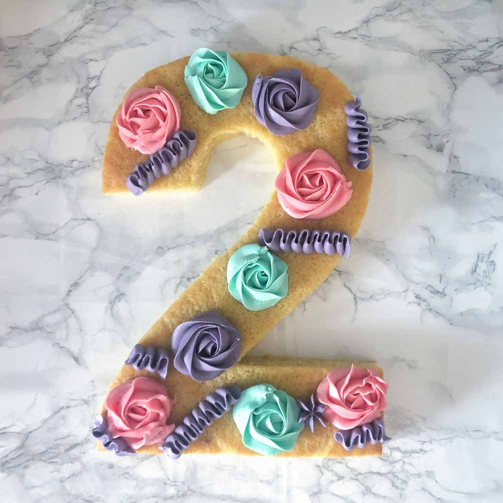 Decorating a lemon vanilla number cake with frosting