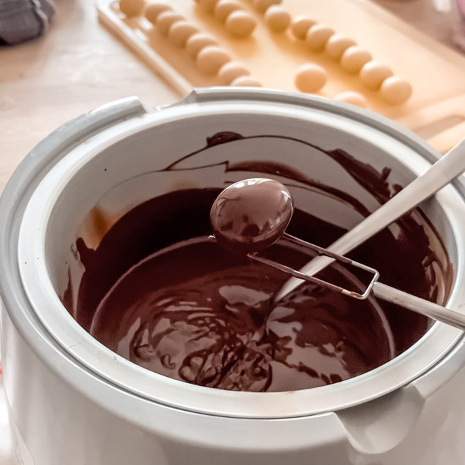 Marzipan Easter egg being dipped in crisp pearl coating
