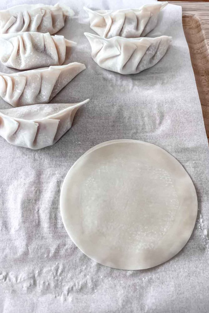 Hands folding gyoza dumpling wrapper into pleats
