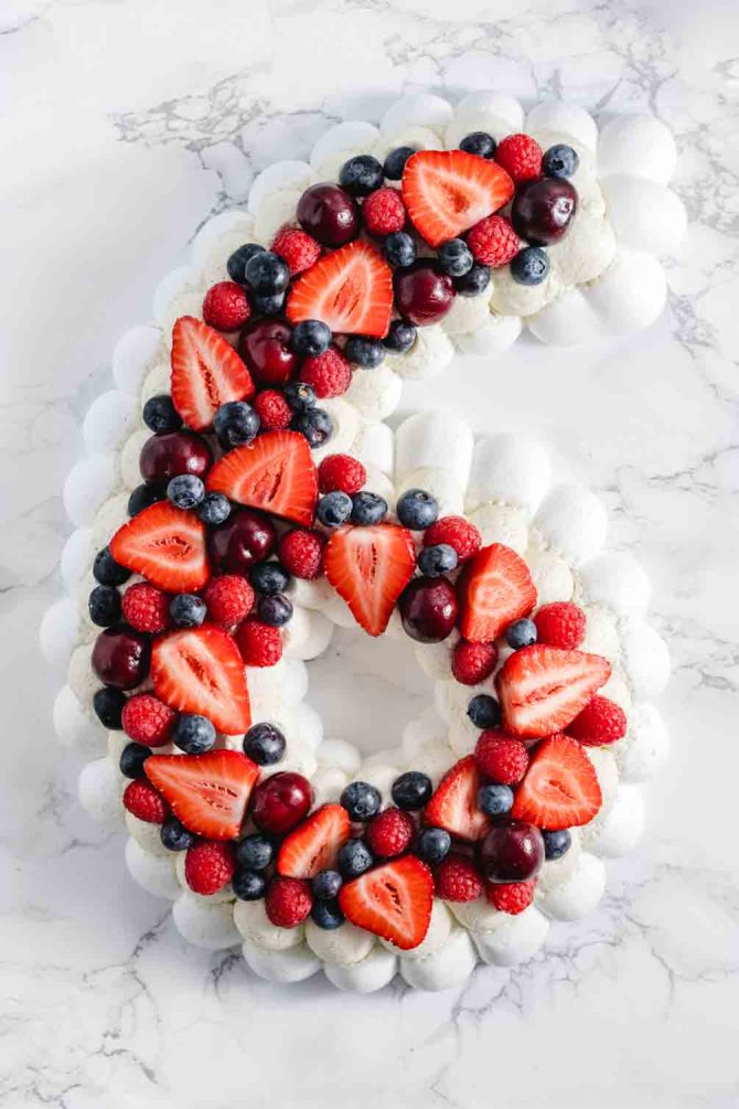 Pavlova number cake layered with fresh summer berries