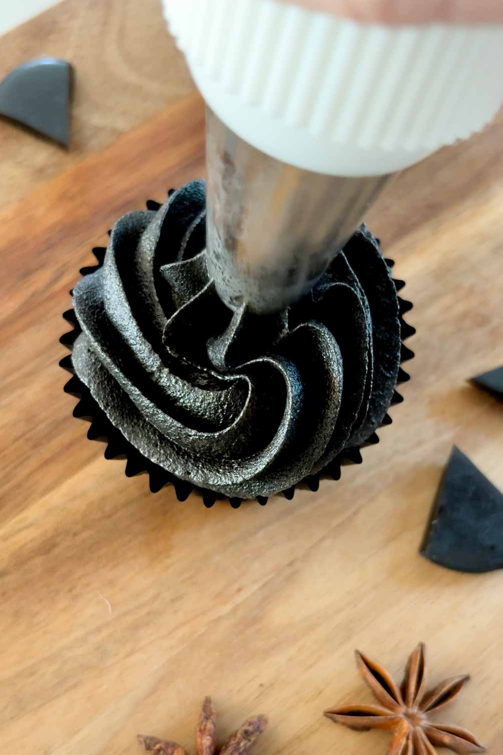 Piping black frosting onto a cupcake for black cat cupcakes