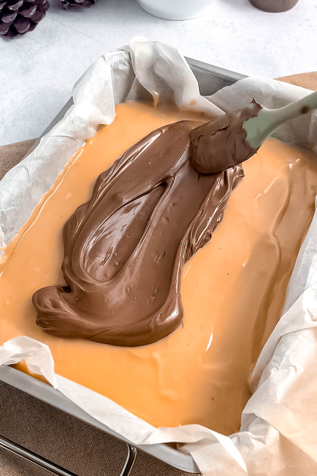 Chocolate coating spread over caramel and shortbread bars